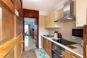 A kitchen with wooden cabinets, a stainless steel sink, and a microwave.