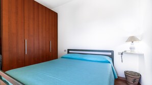 Une chambre à coucher avec un lit, une armoire en bois, une lampe de chevet et un petit panier en osier.