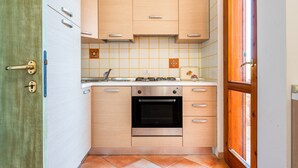 Une cuisine compacte dotée d’un four encastré, d’un évier et d’un pare-feu en carreaux.