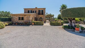 A stone building with a gravel driveway, a small garden with potted plants, and a well-maintained hedge. - Villa 'Toni Mosca' with Mountain View, Wi-Fi and Air Conditioning (Pollensa / Pollença)