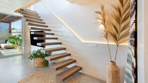 Eine moderne Treppe mit Glaskuppel, die in einen Wohnbereich mit Sofa und Pflanzen führt.