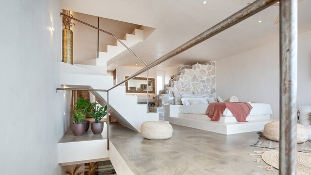 Ein modernes Interieur mit einer Treppe, einem weißen Sofa und einer Steinwand.