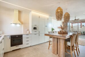 Una cocina moderna con armarios blancos, una isla de madera y lámparas colgantes.