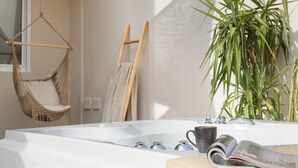Ein modernes Badezimmer mit Badewanne, einer Hängematte, einer Holzleiter und einem Topf mit Pflanze.