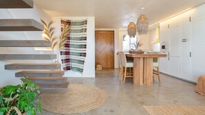 Eine moderne Küche mit einer Holzinsel, eingebauten Schränken und einer Treppe mit freiliegenden Balken.