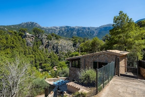 A stone building with a stone staircase, a fenced area, and a view of mountains.