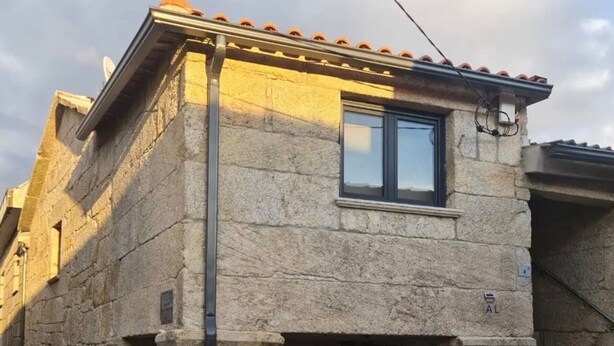 Un edificio in pietra con una finestra, una porta e un piccolo portico.