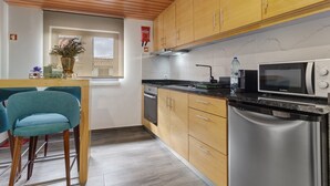 Una cucina moderna con mobili in legno, elettrodomestici in acciaio inossidabile e una sedia blu.