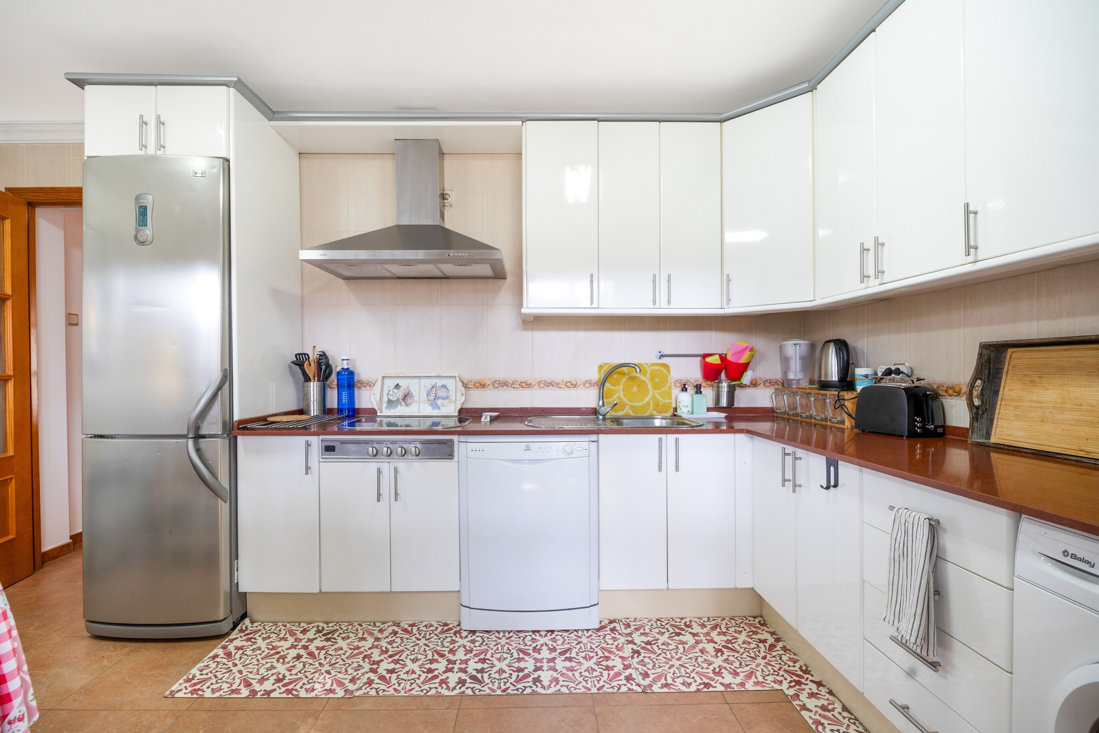 A kitchen with white cabinets, a stainless steel refrigerator, a dishwasher, and a toaster.