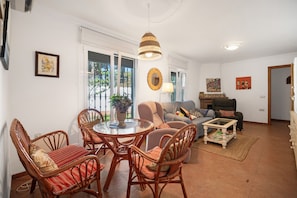 Een woonkamer met rieten meubels, een ronde tafel, een bank en een salontafel.