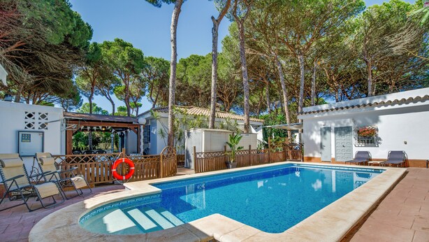A rectangular swimming pool with a tiled deck, surrounded by lounge chairs and a wooden fence. - Villa 'El Limonar' with Shared Pool and Wi-Fi (Chiclana de la Frontera)