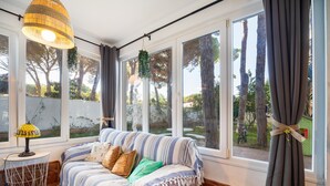 A room with a sofa, a lamp, and large windows with curtains. - Villa 'El Limonar' with Shared Pool and Wi-Fi (Chiclana de la Frontera)