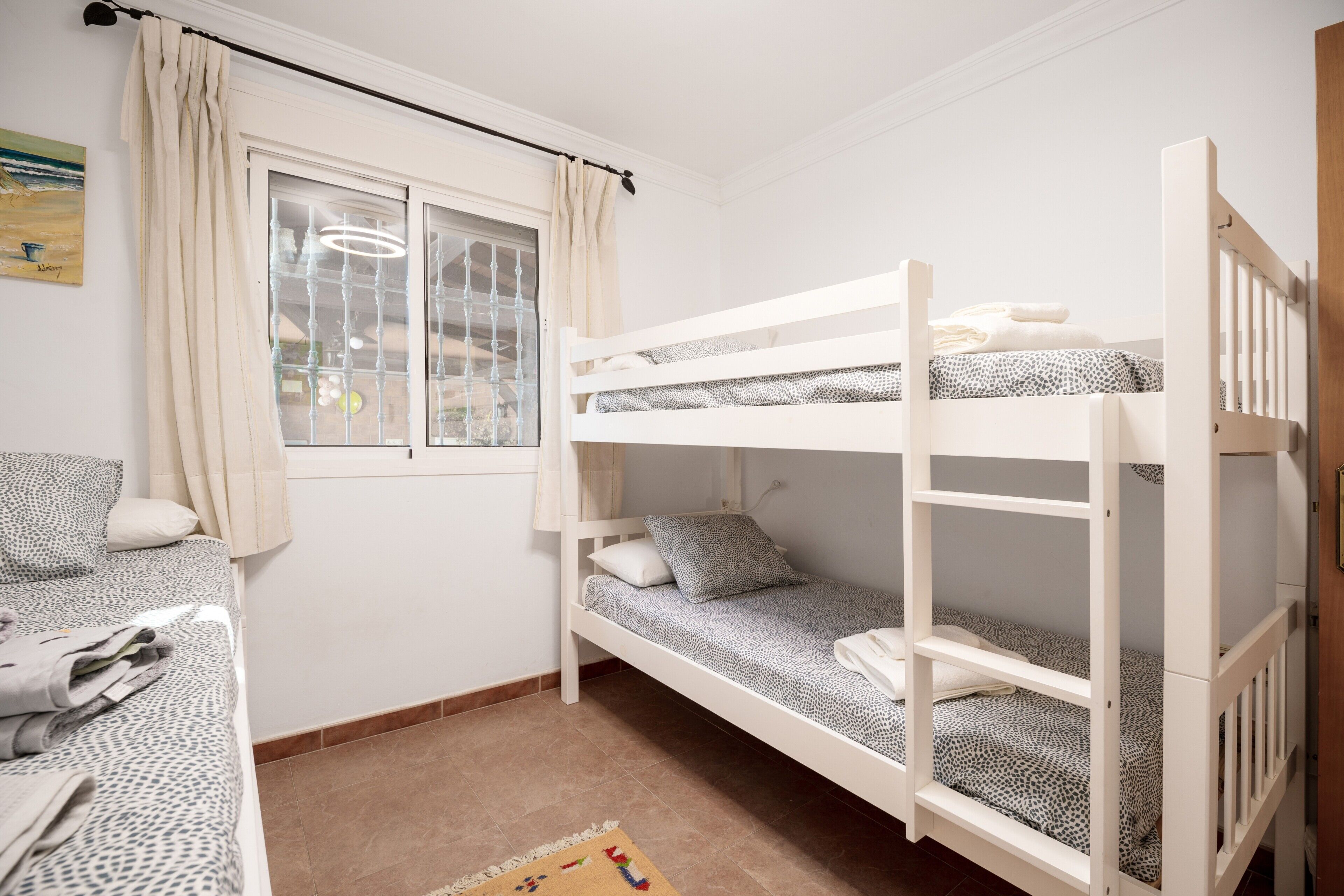 Dormitorio con literas, una ventana, un escritorio y una silla.