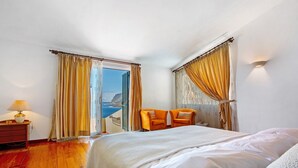 Une chambre à coucher avec un lit, deux chaises, une table de chevet et une lampe.