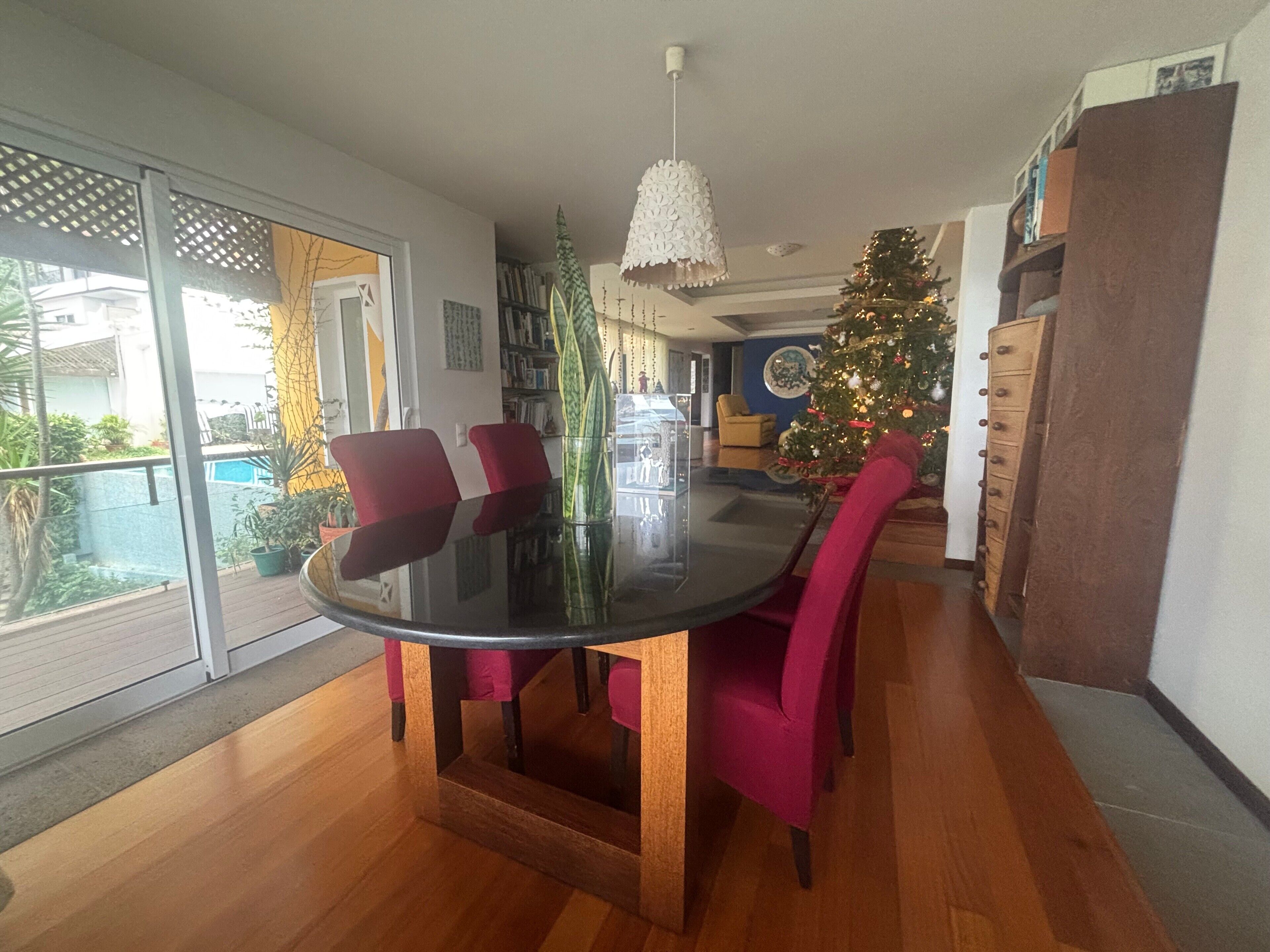 Ein Essbereich mit einem Glastisch, roten Stühlen, einem Weihnachtsbaum und Blick auf einen Pool.
