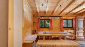 L’intérieur d’un chalet en bois comprend une table à manger, un banc et un coin cuisine.