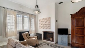 A living room with a sofa, armchairs, a fireplace, a television, and a large wooden cabinet. - Studio Apartment 'Da Linda' with Mountain View and Wi-Fi (Cisano sul neva)
