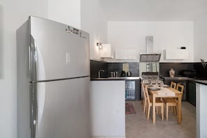 Eine kompakte Küche mit Kühlschrank, Herd, Mikrowelle und Esstisch mit Stühlen.