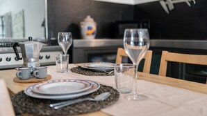 A dining table set with plates, cutlery, and glasses, with a coffee maker and a vase in the background. - Studio Apartment 'Da Linda' with Mountain View and Wi-Fi (Cisano sul neva)