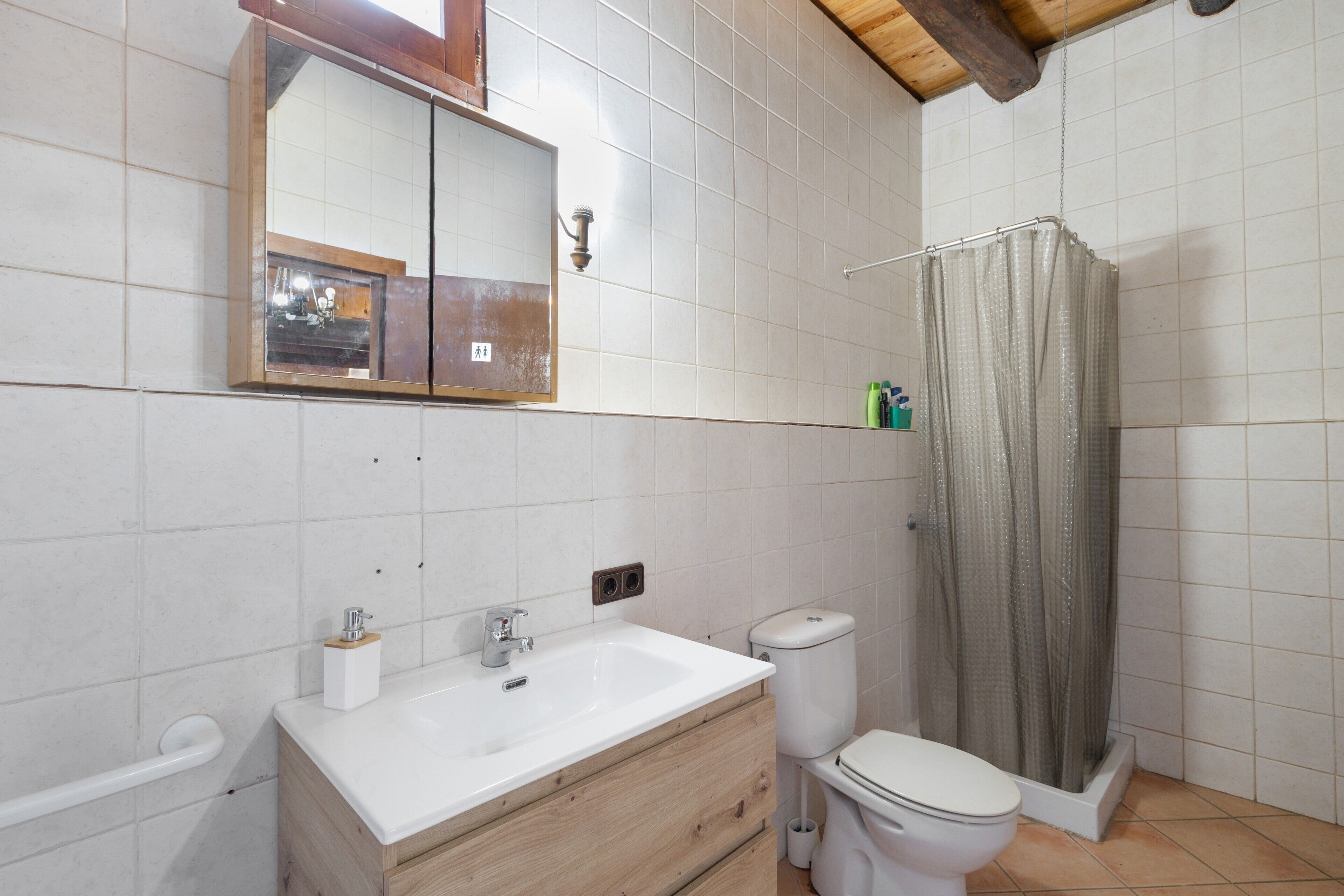 Baño con lavamanos, inodoro y cortina de ducha.