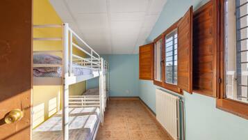 A narrow hallway with bunk beds, a radiator, and wooden shutters on the windows.