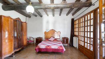 Un dormitori amb sostre de fusta, un llit amb colcha, un armari i una finestra amb vista.