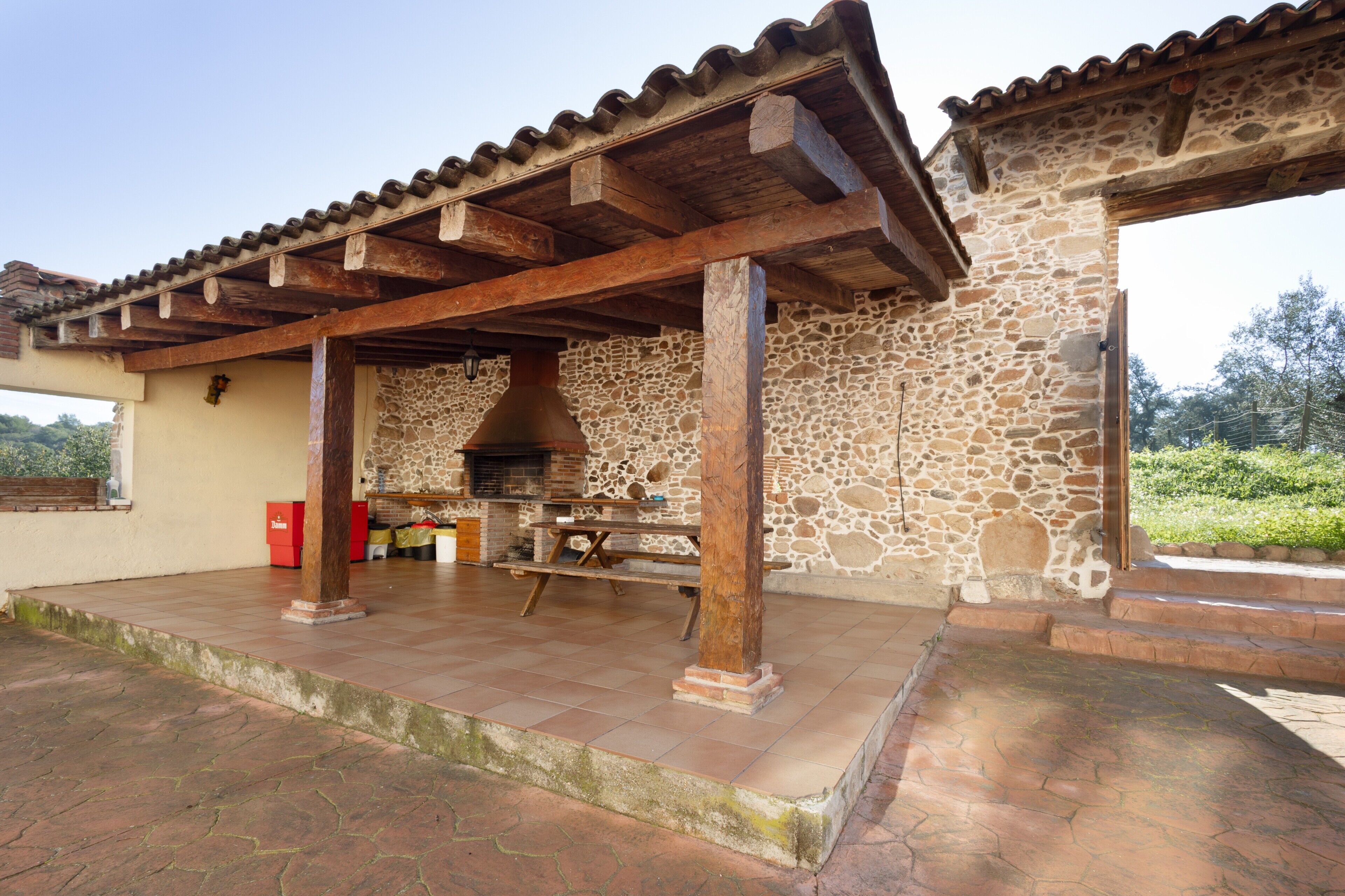Un bâtiment en pierre doté d’un patio carrelé, de poutres en bois et d’un mur en pierre.