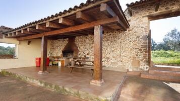 Un bâtiment en pierre doté d’un patio carrelé, de poutres en bois et d’un mur en pierre.