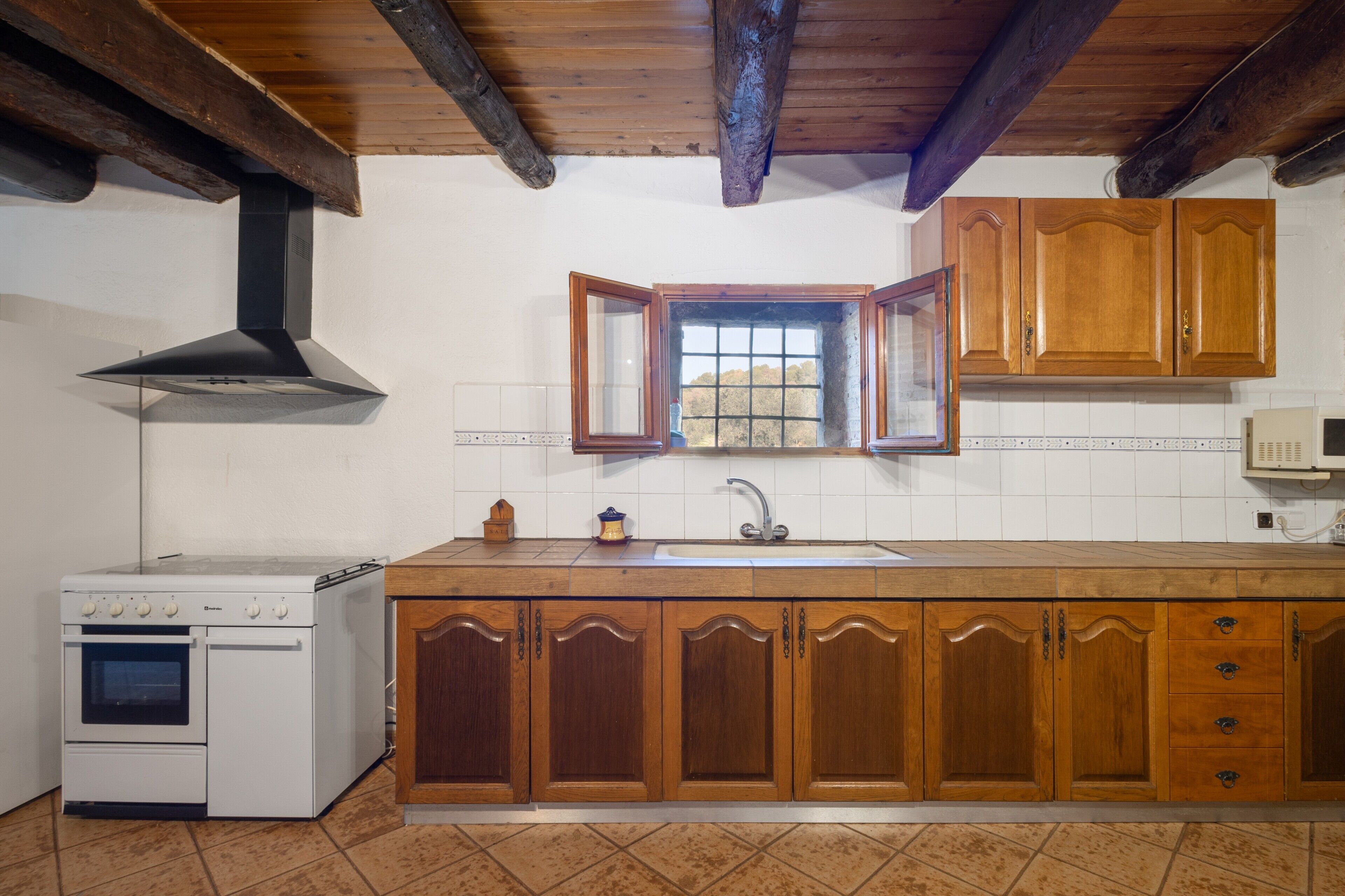 A kitchen with wooden cabinets, a white stove, a window with a view, and a tiled backsplash.