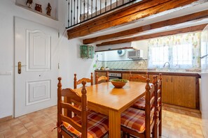 Un'area pranzo con un tavolo e sedie in legno, una cucina sullo sfondo e una porta bianca.