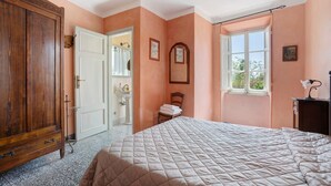 A bedroom with a large bed, a wardrobe, a window, and a door leading to a bathroom. - Apartment 'Appartamento Paggio' with Shared Pool and Air Conditioning (Massarosa)