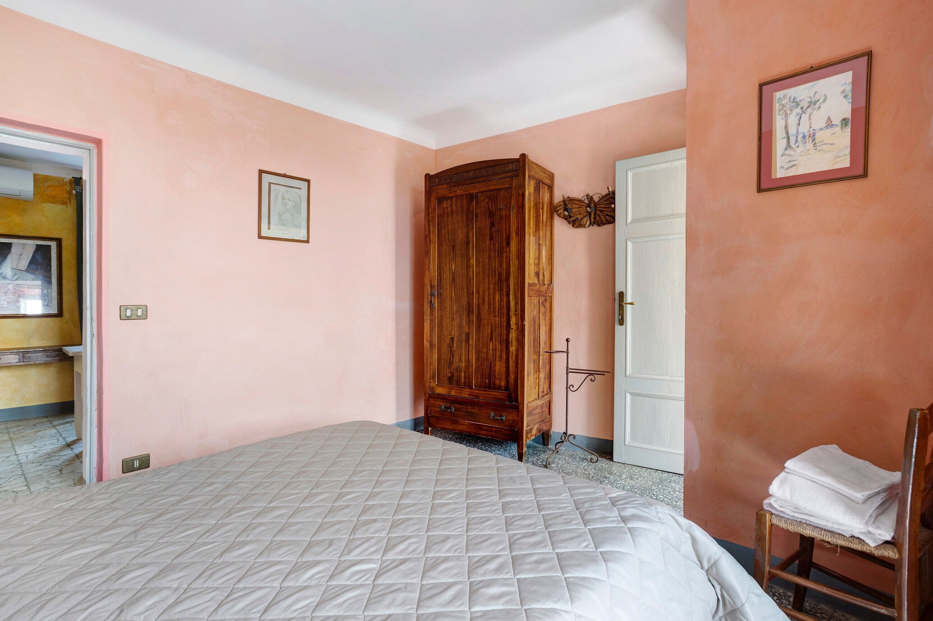 Un dormitorio con una cama, un armario de madera, una puerta y una silla.