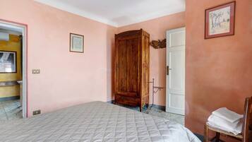 Un dormitorio con una cama, un armario de madera, una puerta y una silla.