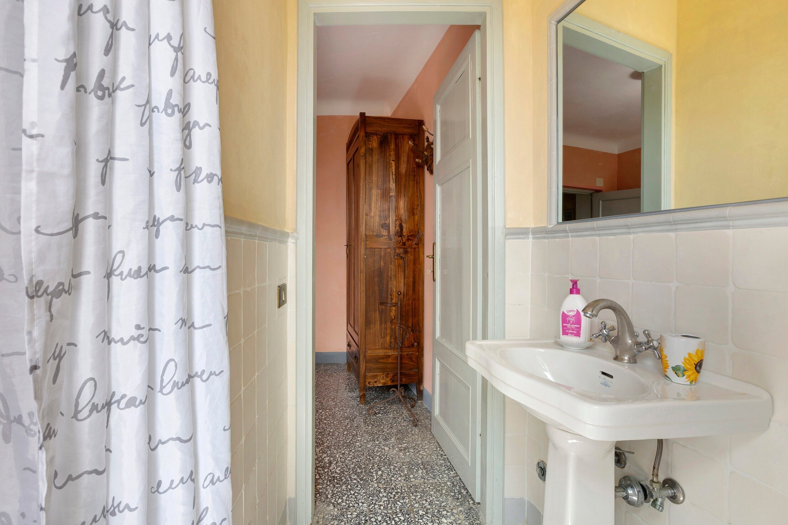 Un bagno con lavandino, specchio e tenda per la doccia.