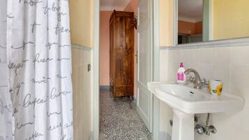 Un bagno con lavandino, specchio e tenda per la doccia.