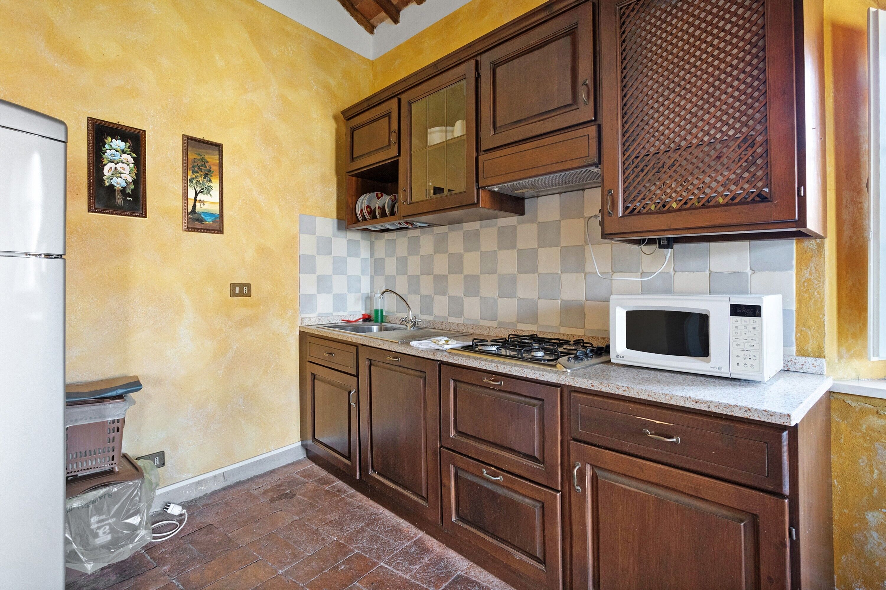 Una cucina con mobili in legno, un forno a microonde e uno schienale piastrellato.