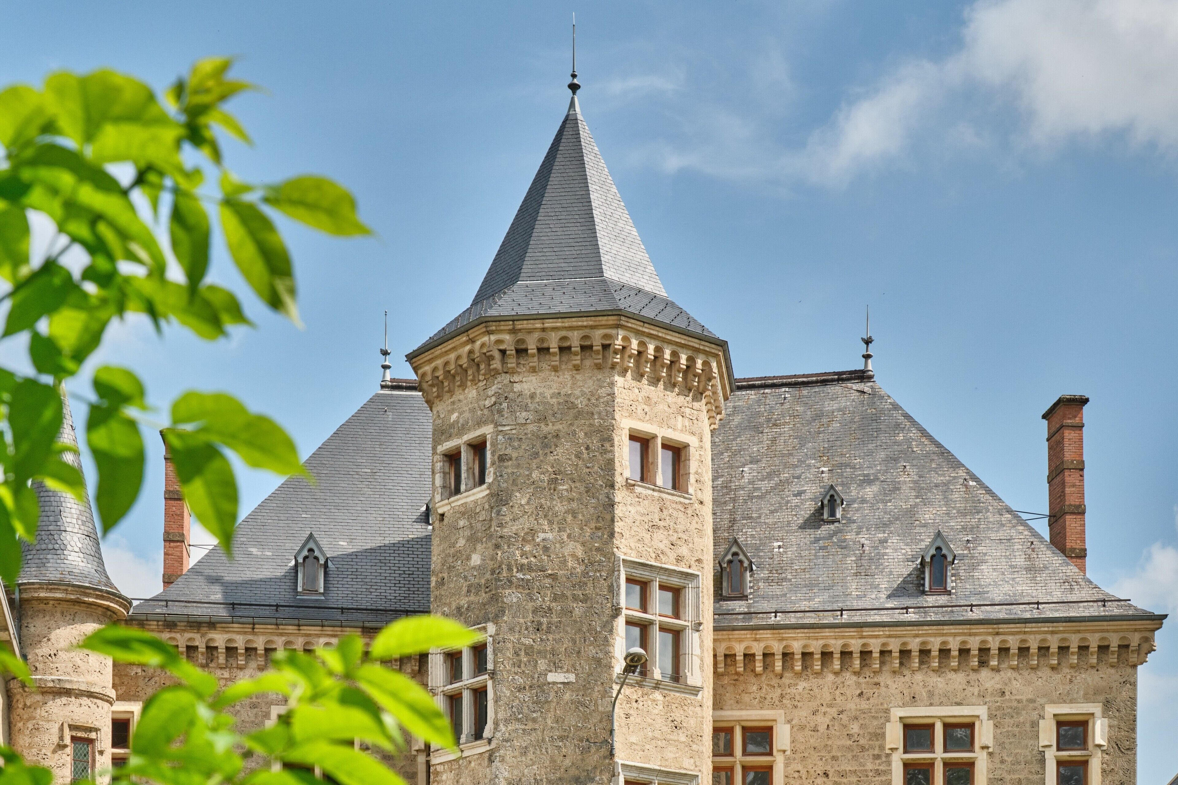 Ein historisches Gebäude mit einem markanten Turm, zahlreichen Fenstern und einer Steinfassade.