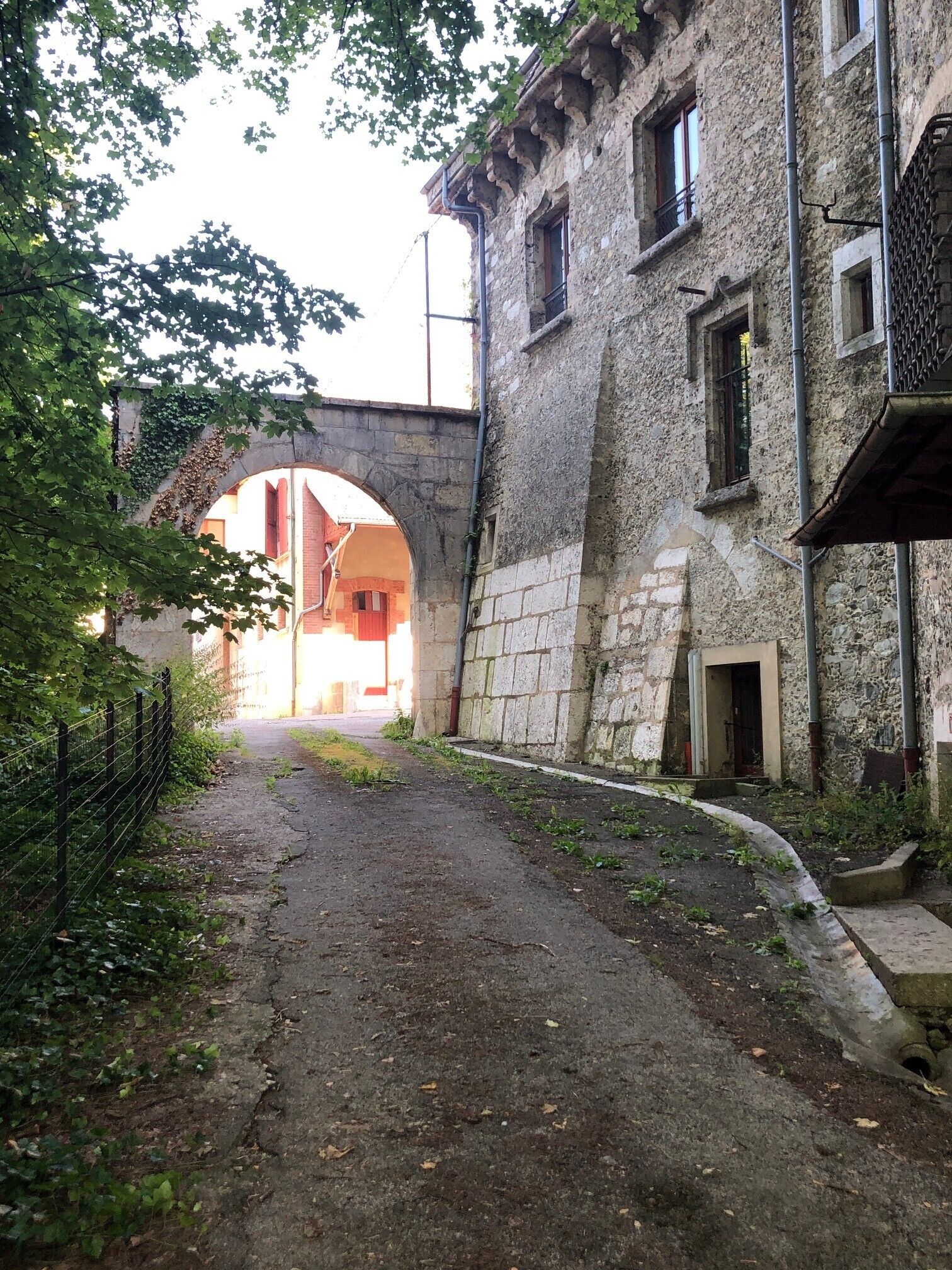 Ein schmaler Gang, einerseits ein Gebäude aus Stein, andererseits ein Backsteinhaus. Ein steinernes Portal verbindet die beiden Gebäude.