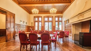Una sala de conferencias con paneles de madera, ventanas amplias y una chimenea.