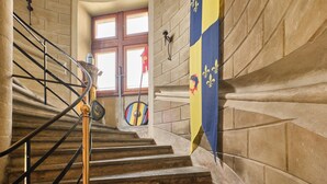 Una escalera con barandilla, paredes de piedra y una bandera.
