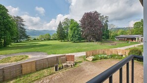 A view of a property with a large lawn, wooden fences, and a building with outdoor seating.