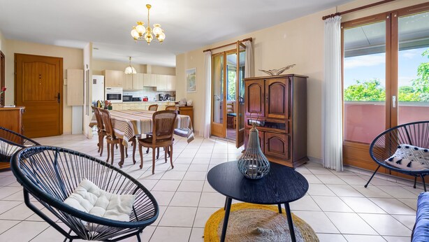 Amplia sala de estar con una mesa de comedor, sillas, un sofá y una cocina al fondo.