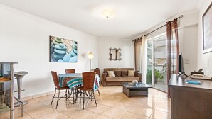 A modern living room with a dining area, a sofa, a coffee table, and a TV. - Apartment 'Superbe Appartement Vue Mer' with Sea View, Wi-Fi and Air Conditioning (Fréjus)