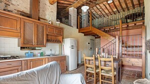 A rustic kitchen with wooden cabinets, a dining table, and a sofa. - Apartment 'Appartamento Torre' with Shared Pool, Shared Garden and Wi-Fi (Massarosa)