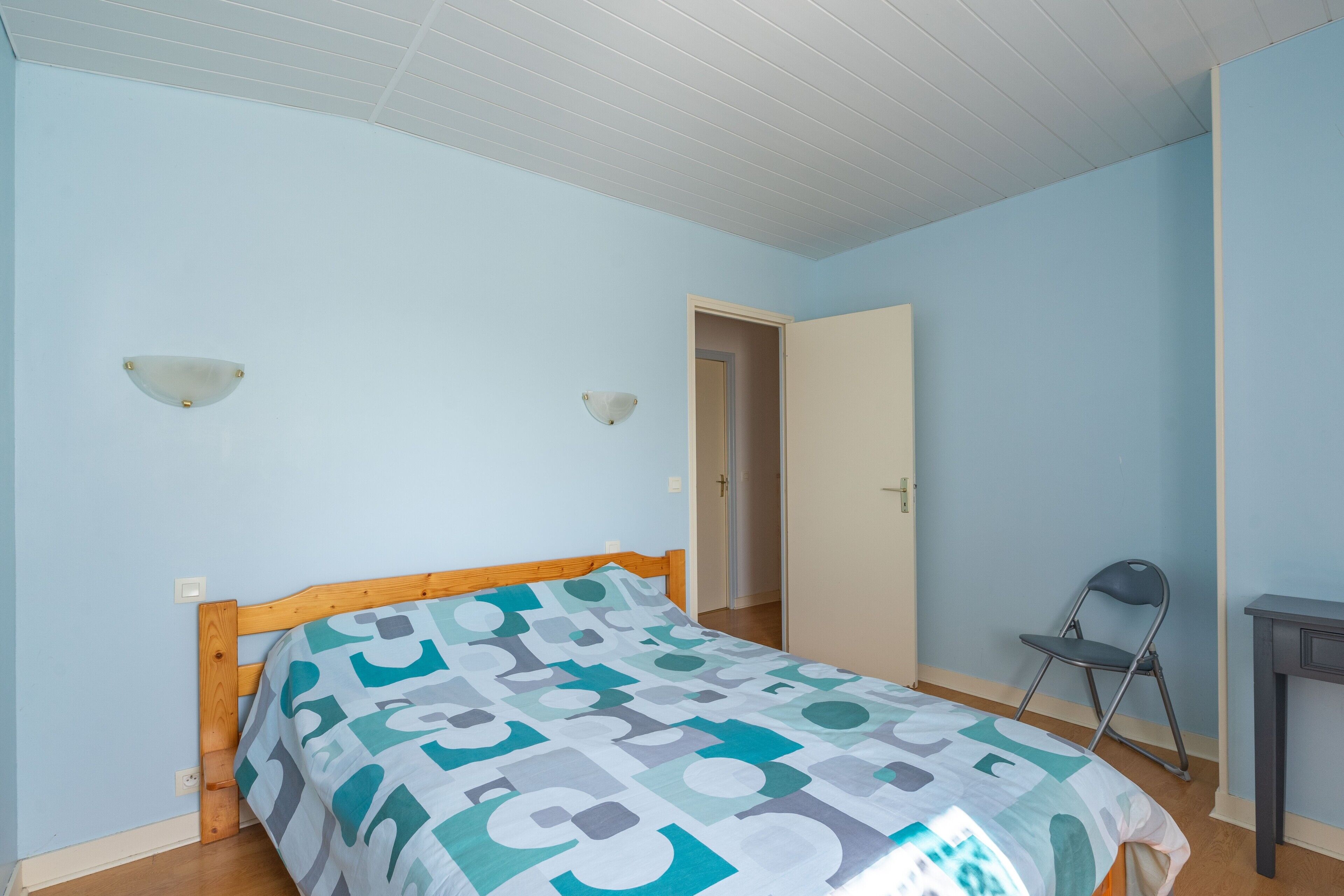 A bedroom with a bed, a chair, and a door.