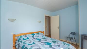 A bedroom with a bed, a chair, and a door.