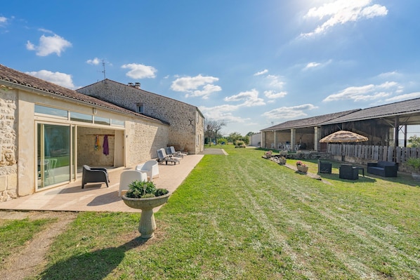 A stone building with a patio, outdoor seating, and a grassy yard.