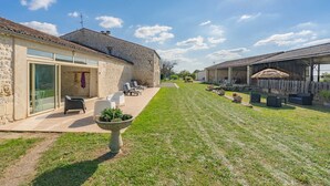 Un bâtiment en pierre doté d’un patio, d’un espace extérieur aménagé pour s’asseoir et d’une pelouse bien entretenue.
