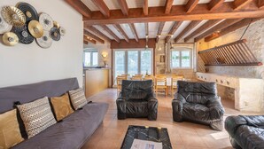 Un salon comprenant un canapé, deux fauteuils en cuir, une table basse et un mur décoré d’assiettes.