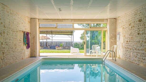 Une piscine avec vue sur une pelouse et une terrasse couverte.